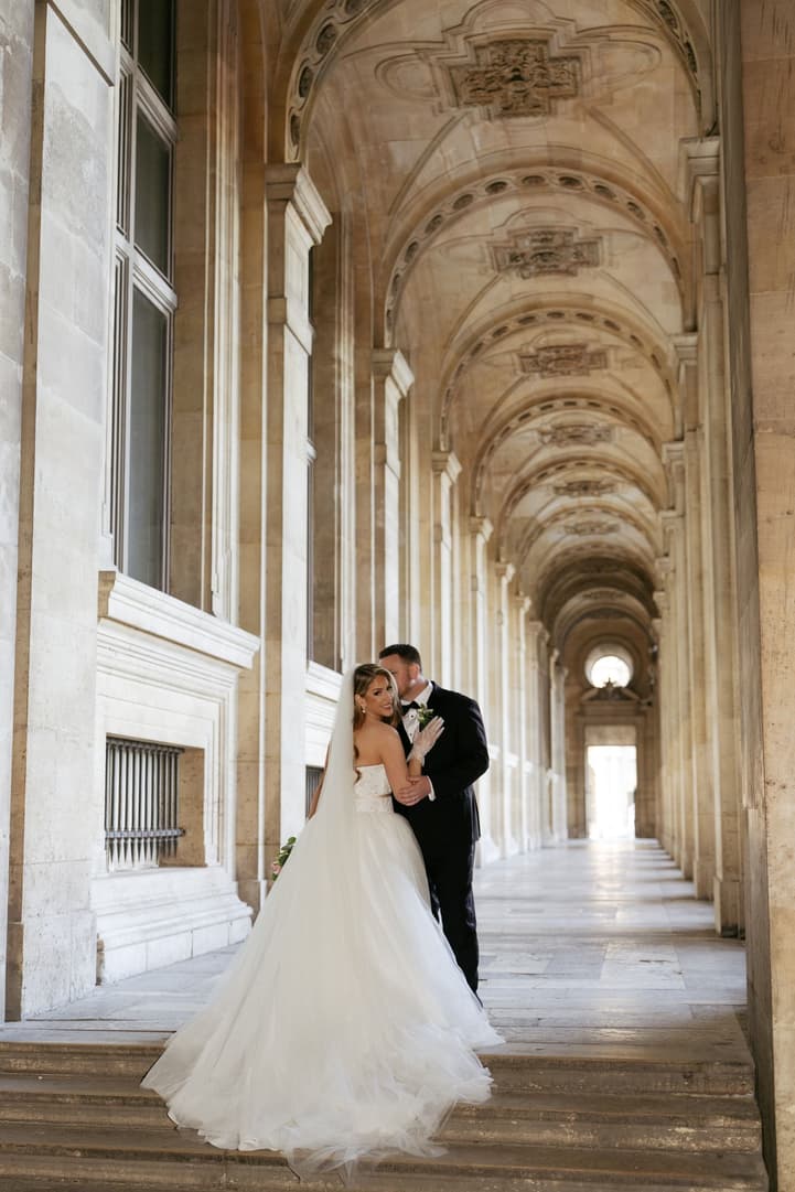 Aphrodite and Michael kissing at the end of the hallway of the Louvre