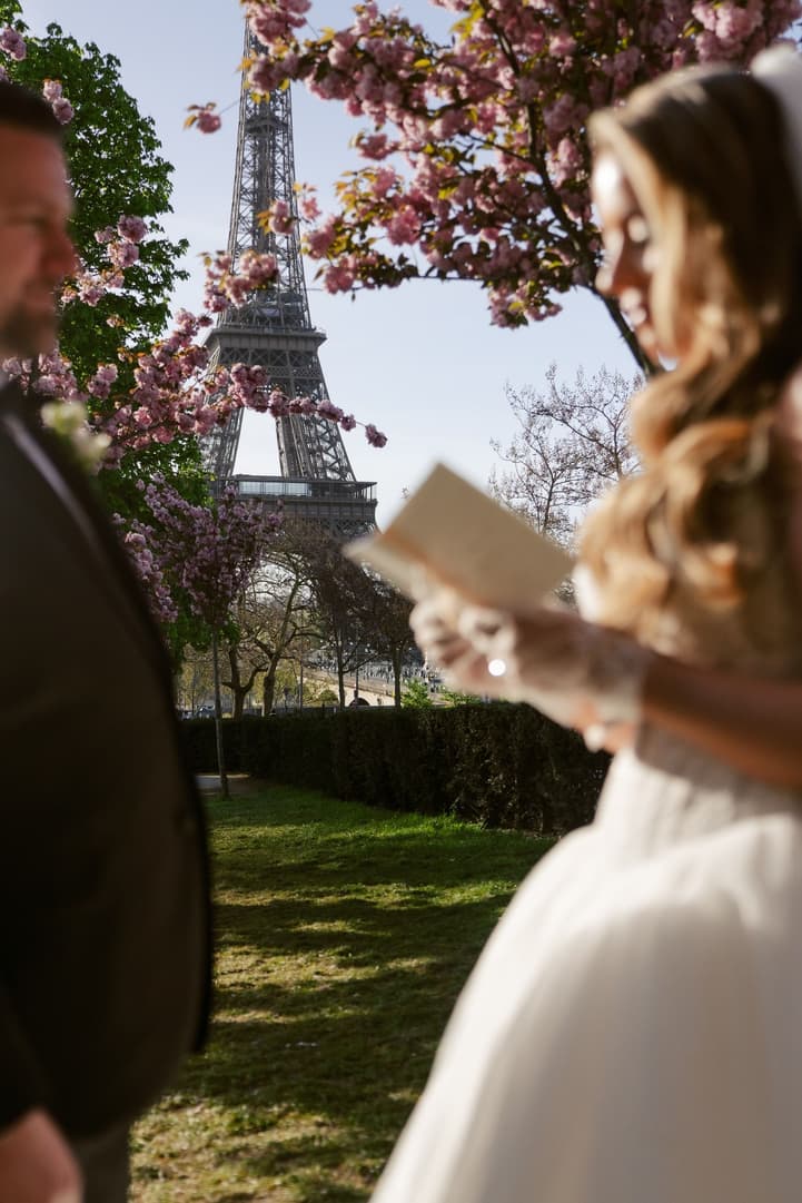 Aphrodite reading her vows from a vow book, the Eiffel Tower behind