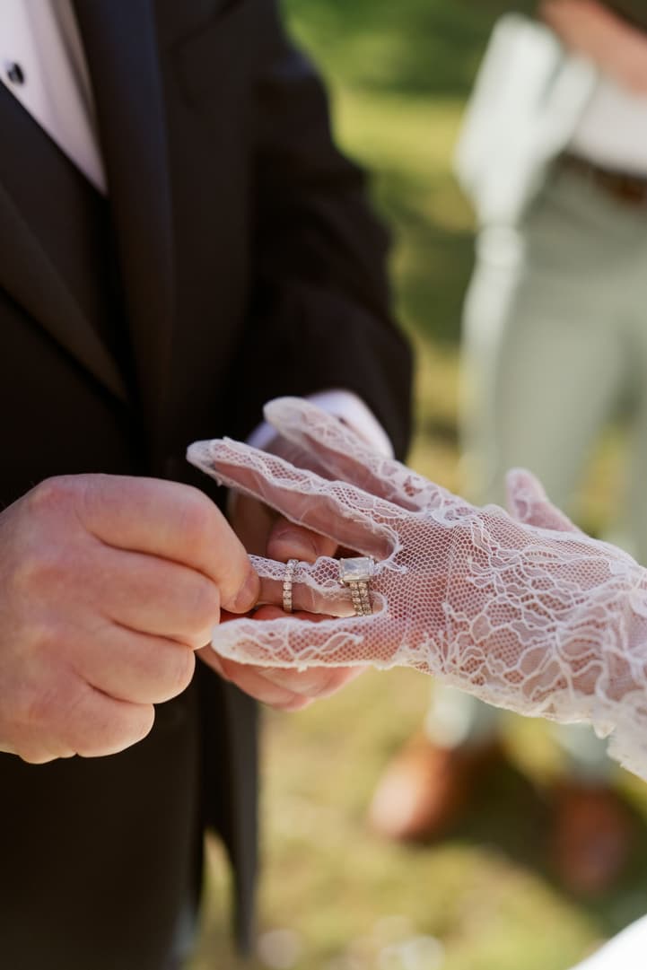 Michael slipping the wedding ring on over Aphrodite's lace glove
