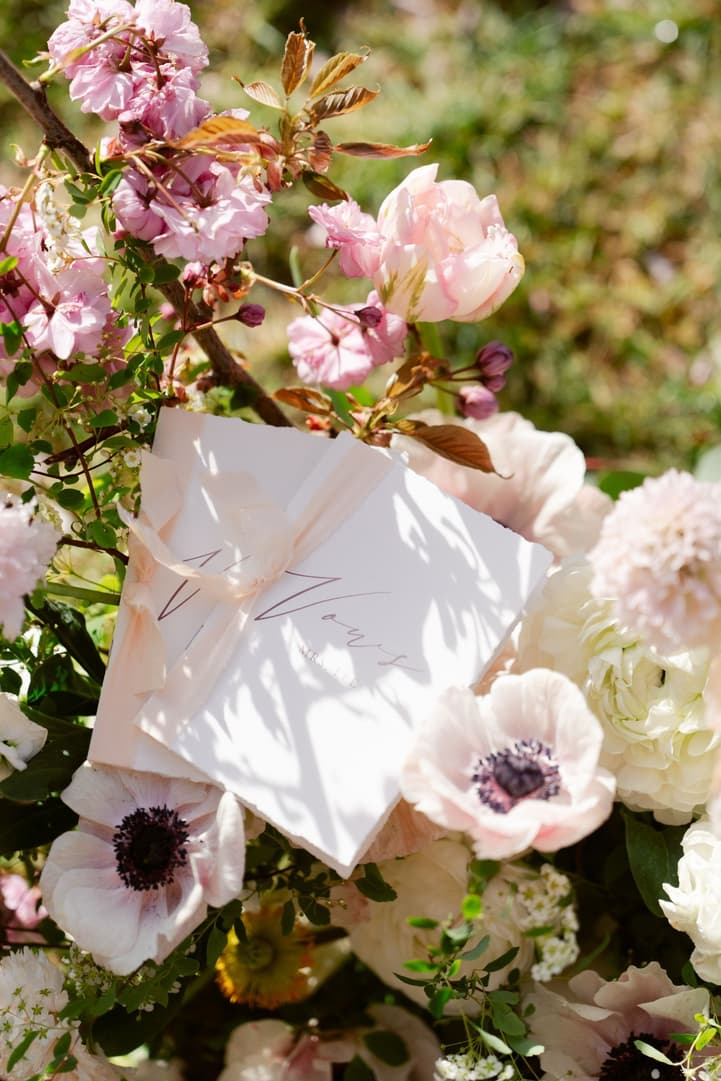 Their vow book tucked into the ceremony flowers among anemones and roses
