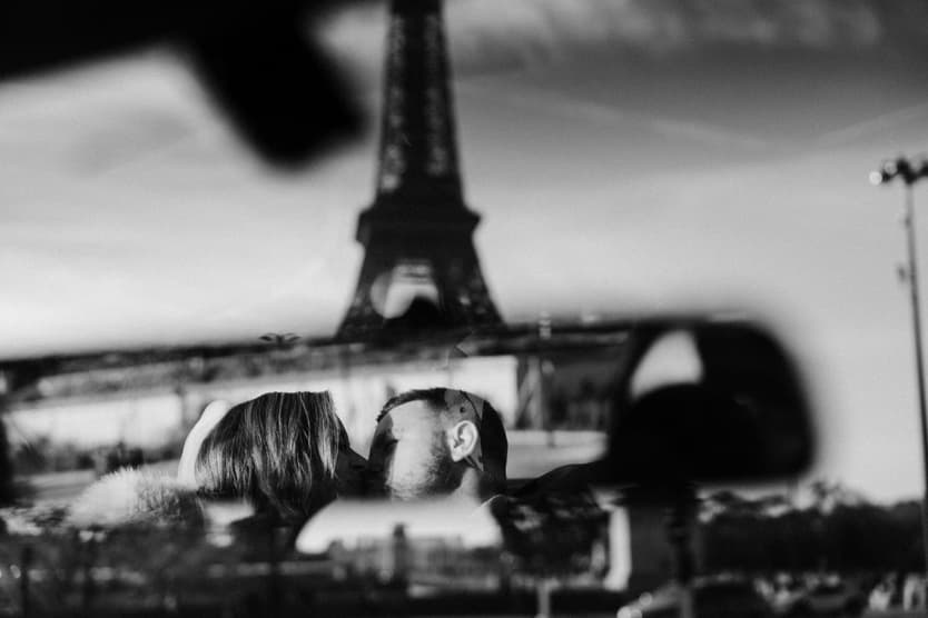 Aphrodite and Michael's kiss reflected in the car's rear-view mirror with the Eiffel Tower
