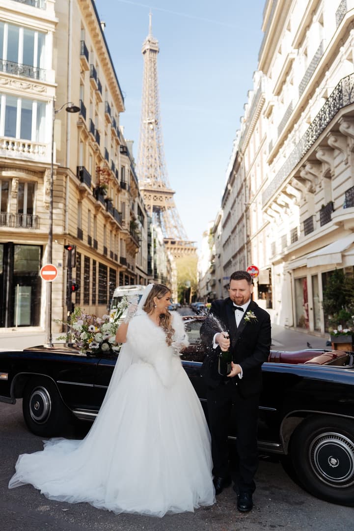 Aphrodite and Michael beside the vintage car on a Paris street with the Eiffel Tower