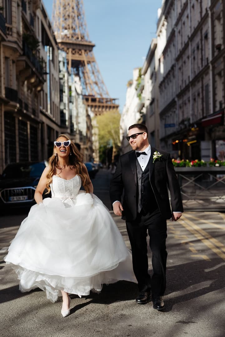 Aphrodite in heart-shaped sunglasses walking with Michael towards the Eiffel Tower