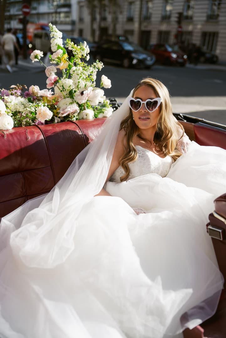 Aphrodite in heart sunglasses in the back of the vintage car