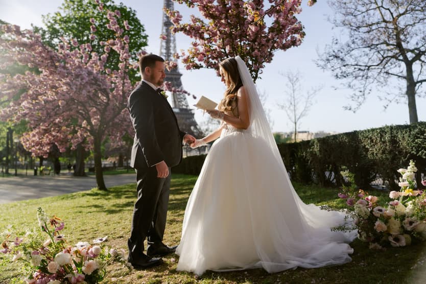Michael and Aphrodite exchanging vows under pink cherry blossoms with the Eiffel Tower