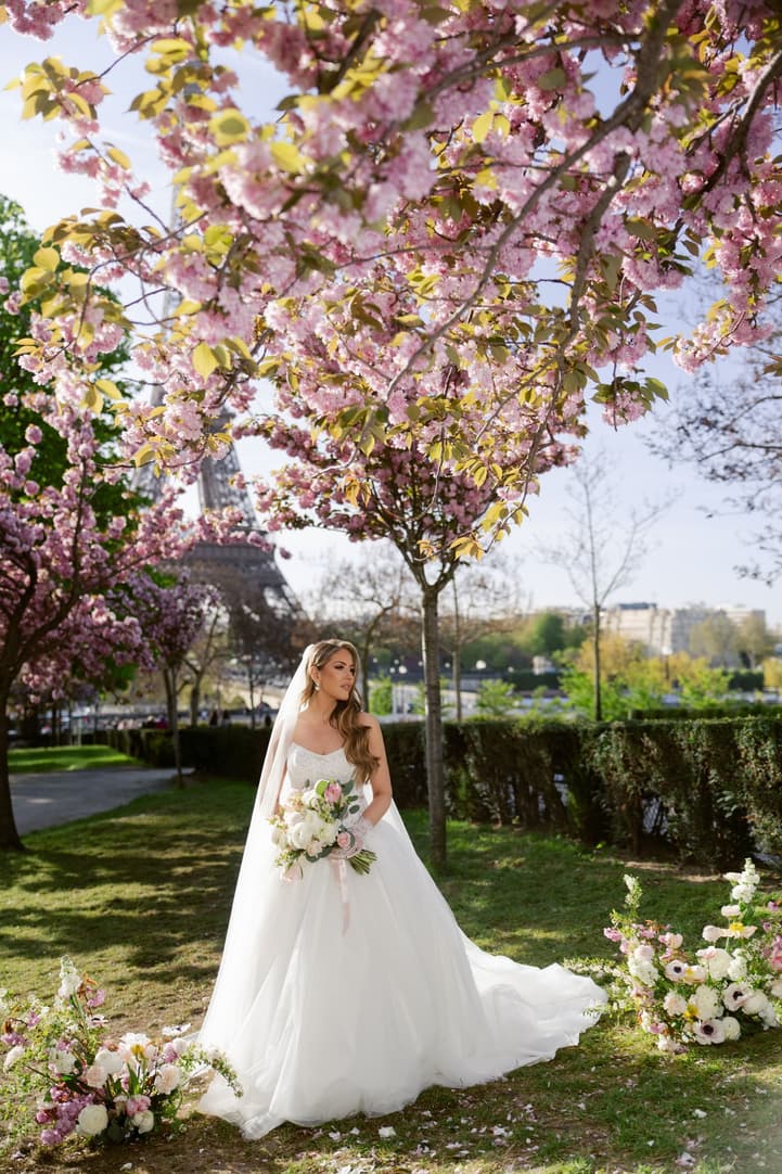 Aphrodite alone under the cherry trees with the Eiffel Tower in the distance