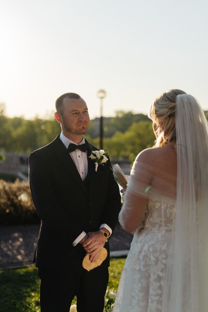 Tyler holds his vow book and listens to Victoria during their ceremony in the Trocadéro gardens