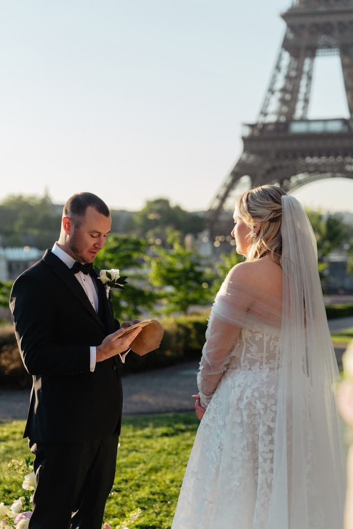Tyler reads his personal vows to Victoria, the Eiffel Tower behind them in the Trocadéro gardens