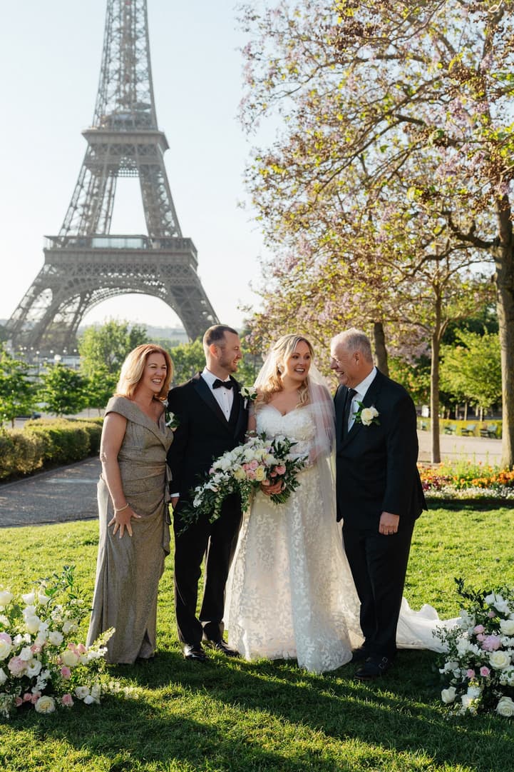 Victoria and Tyler with family by the ceremony flowers, the Eiffel Tower over the Trocadéro gardens