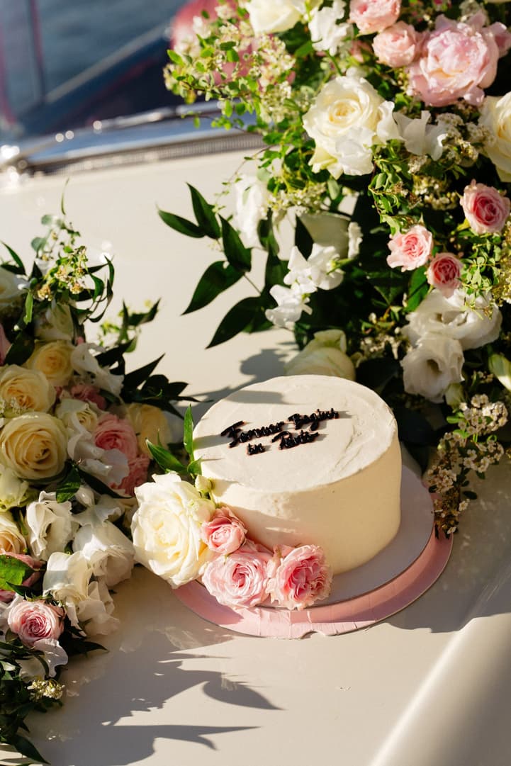 A white cake reading Forever Begins in Paris, set on the vintage car with pale pink roses