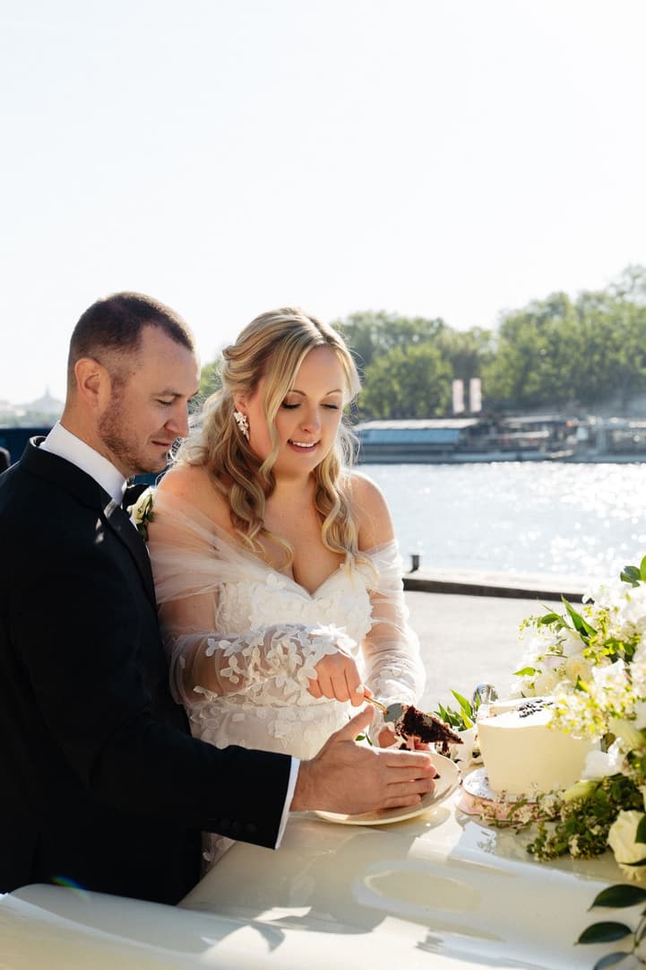 Victoria and Tyler cut their wedding cake on the bonnet of the vintage car by the Seine