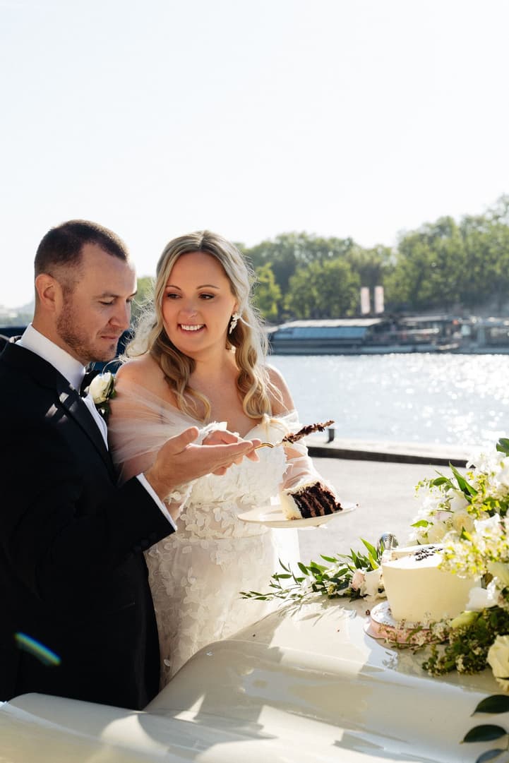 Victoria and Tyler share their first slice of wedding cake beside the Seine