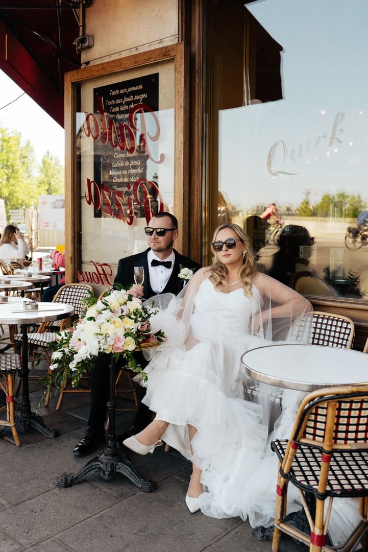 Victoria and Tyler in sunglasses on woven café chairs at La Frégate in Paris