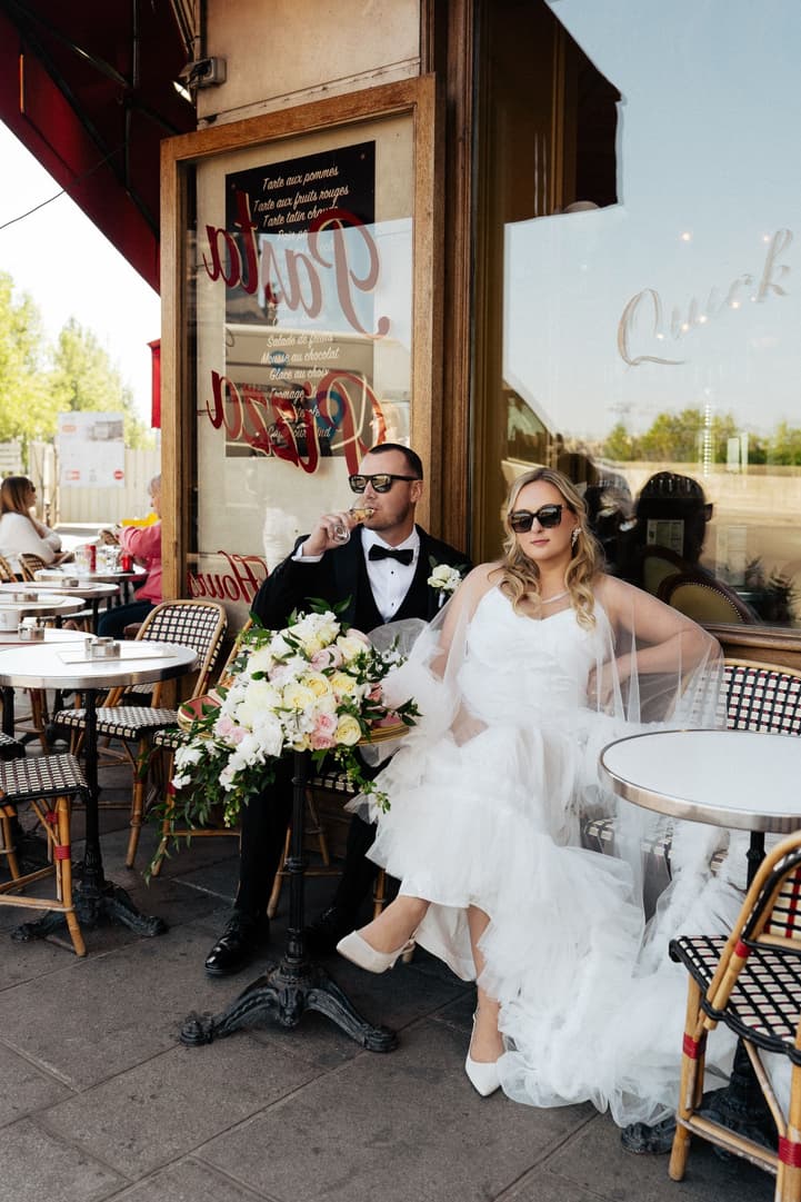 Tyler sips Champagne beside Victoria in her ruffle cape on the terrace of La Frégate