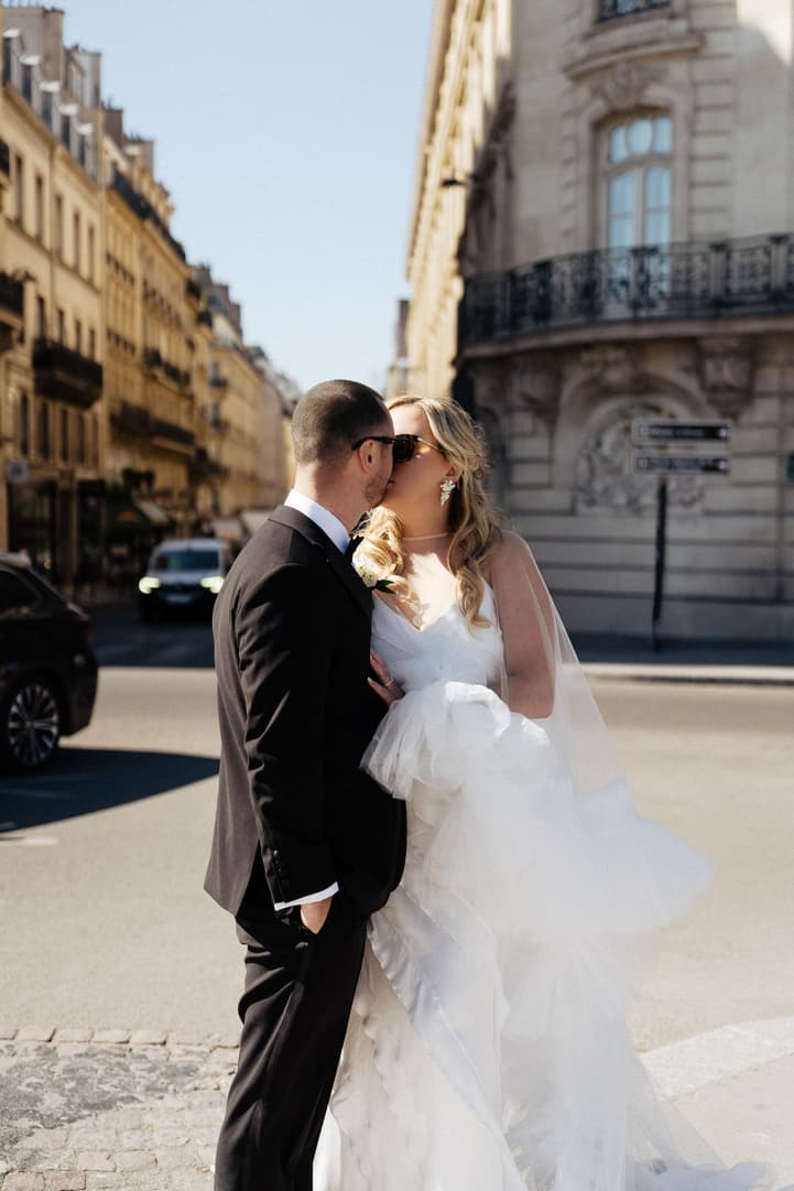 Victoria and Tyler kiss on a Paris street lined with Haussmann buildings