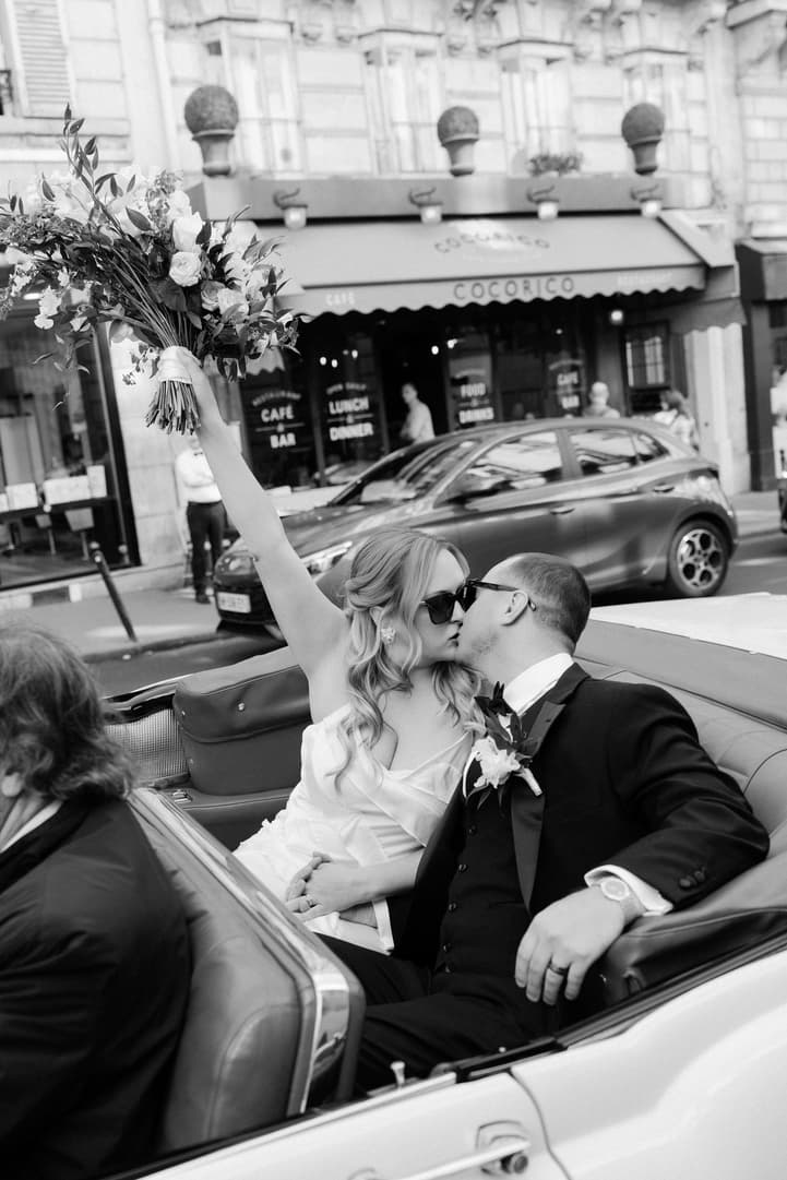 Black and white: Victoria raises her bouquet as she kisses Tyler in the white vintage convertible