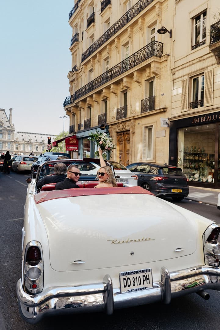 Victoria and Tyler ride through Paris in the white vintage convertible, her bouquet held high