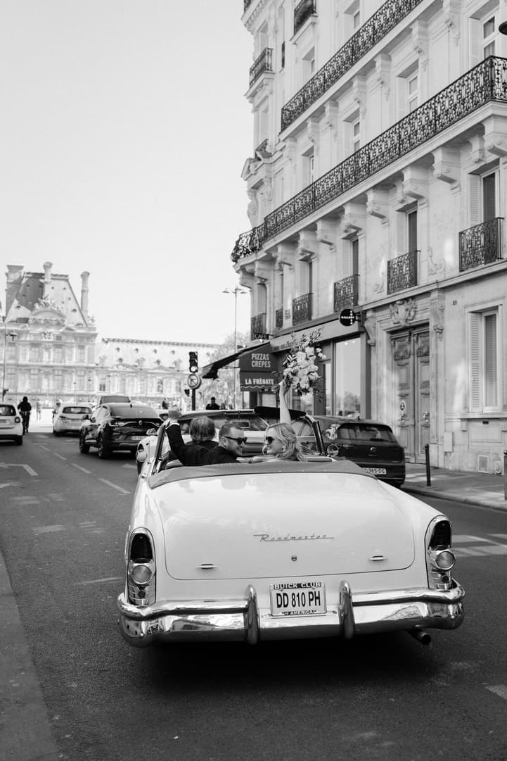 Black and white: the white vintage convertible drives Victoria and Tyler down a Paris street toward the Louvre