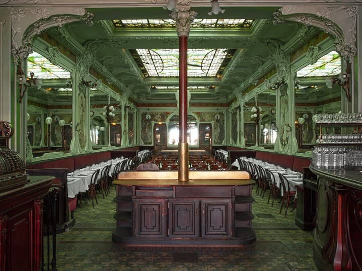 The long Art Nouveau dining room of Bouillon Julien, its celadon walls, glass skylights and carved wooden bar