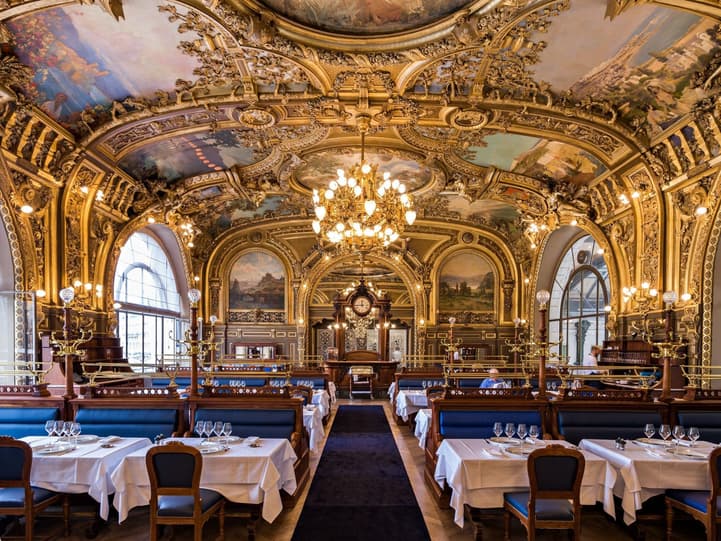 Le Train Bleu's gilded dining room at the Gare de Lyon, its painted ceilings, chandelier and blue banquettes