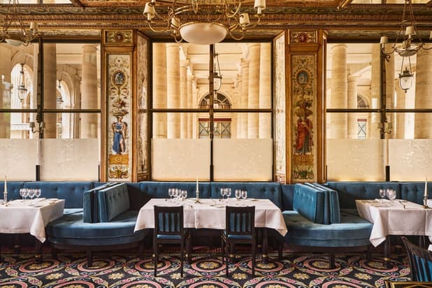 Le Grand Véfour's dining room: blue velvet banquettes, painted panels and the Palais-Royal's columns through the windows