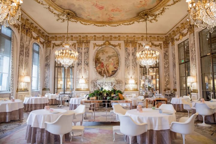 The dining room of Restaurant le Meurice: crystal chandeliers, a painted ceiling, gilded mouldings and white tables